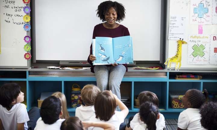 a teacher with a book working with their students